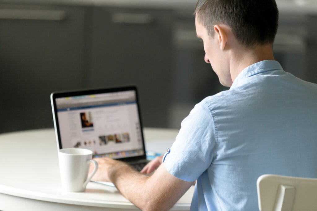 Portrait of a young man working at desk with laptop - Bidaya Global